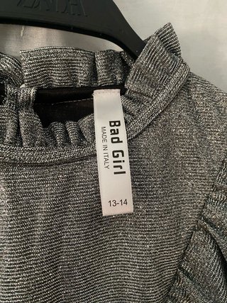 Blusa gris metalizada de manga larga con volantes.
