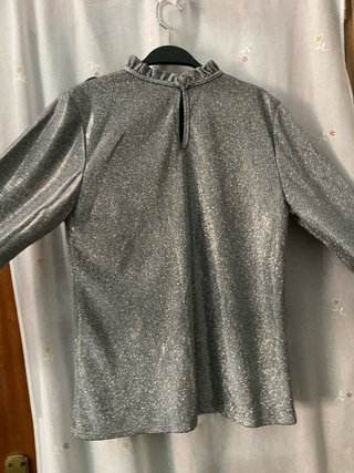 Blusa gris metalizada de manga larga con volantes.