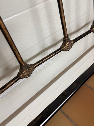 Cabecero antiguo de metal con detalles de latón