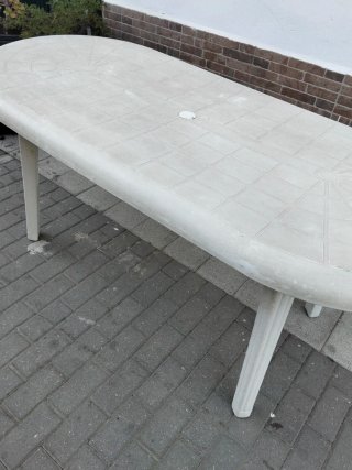 Mesa de jardín ovalada blanca y cuatro sillas.