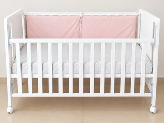 Cuna de bebé blanca con protector rosa