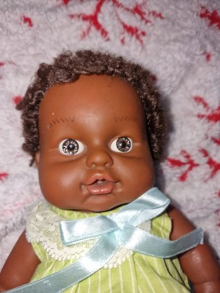 Muñeca bebé morena con vestido verde