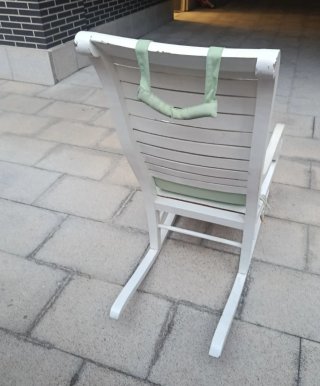 Mecedora de madera blanca y cojines verdes