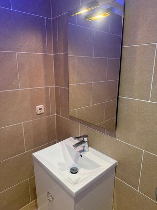 Mueble de baño con lavabo, grifo, espejo.