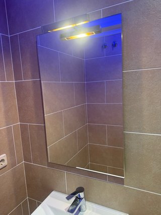 Mueble de baño con lavabo, grifo, espejo.