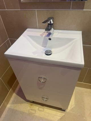 Mueble de baño con lavabo, grifo, espejo.