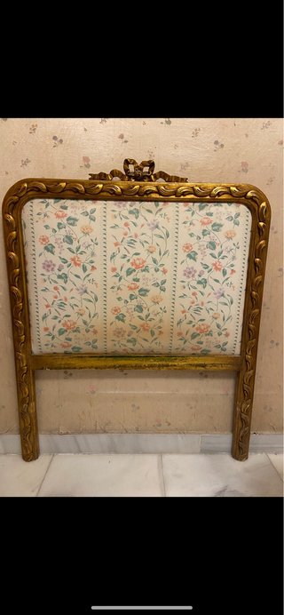 Cabecero de madera dorado con tela floral.