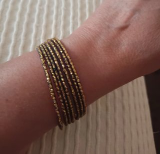 Semanario de pulseras doradas con detalles negros.
