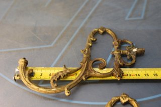 Tres apliques, tiradores, asas o adornos de bronce o latón.