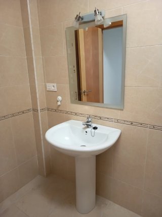 Lavabo de baño con espejo e iluminación y grifo.