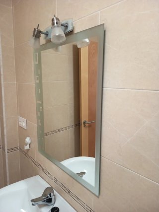 Lavabo de baño con espejo e iluminación y grifo.