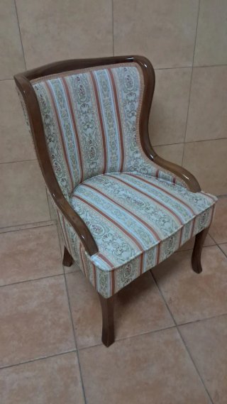 Pequeño sillón clásico de tela y madera.
