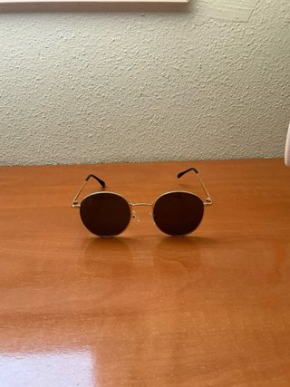 Gafas de sol redondas doradas y negras.