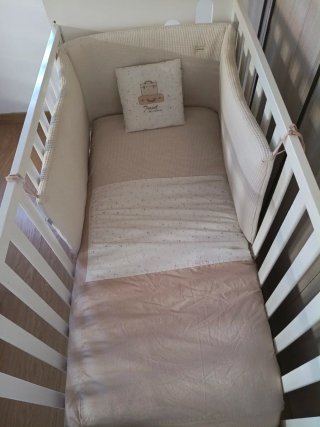 Cuna bebé blanca completa con colchón y textil.