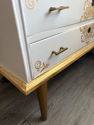 Cómoda blanca y dorada con detalles