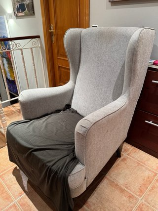Sillon orejero tapizado en tela color gris.