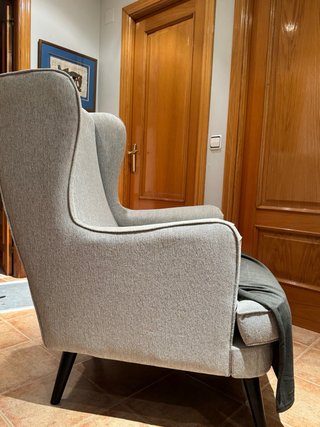 Sillon orejero tapizado en tela color gris.