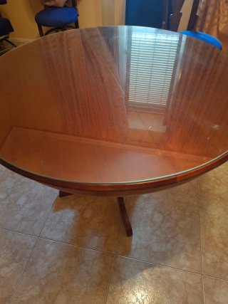 Mesa redonda de salón madera y tiene un cristal