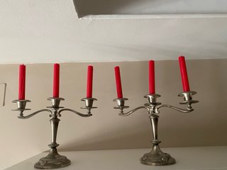 Candelabros de metal plateado con velas rojas