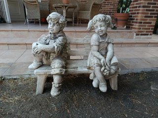 Figura de piedra de niños sentados en banco