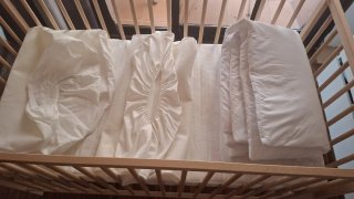 Cuna de bebé de madera con colchón y sábanas