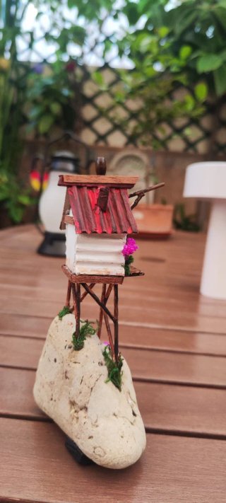 Casita de madera y piedra con flores.
