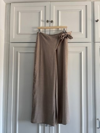 Pantalones fluidos beige con lazo y etiqueta.