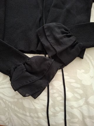 Chaqueta negra con volantes en manga y hombro