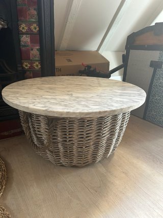 Mesa redonda con tapa de mármol y base de mimbre.