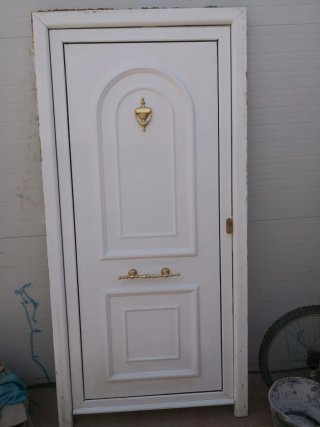 Puerta de entrada blanca con pomo dorado