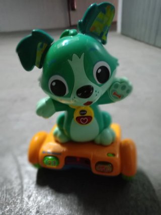 Juguete perro verde con patinete