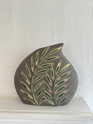 Figura cerámica decorativa con hojas verdes