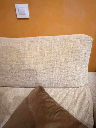 Sofá de tela beige con cojines marrones