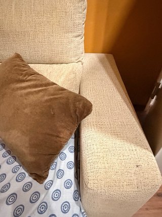Sofá de tela beige con cojines marrones