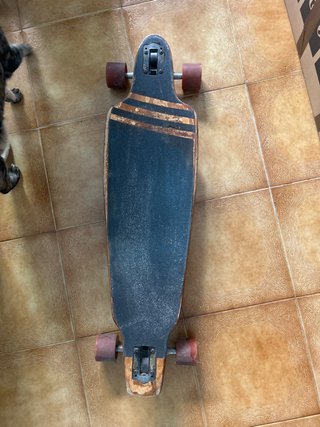 Longboard con ruedas naranjas.