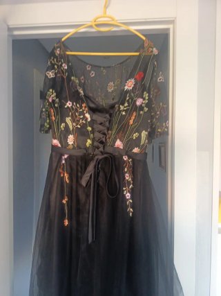 Elegante vestido negro bordado floral.