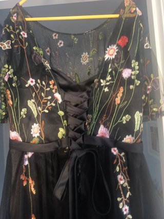 Elegante vestido negro bordado floral.