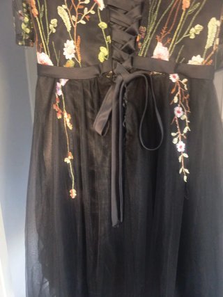 Elegante vestido negro bordado floral.