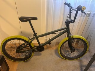 Bicicleta BMX verde con ruedas amarillas.