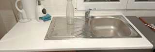 Mueble de cocina blanco, con pila y grifo