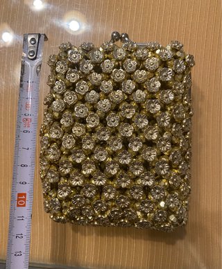 Bolso monedero dorado con pedrería.