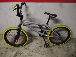 Bicicleta BMX plateada con ruedas amarillas