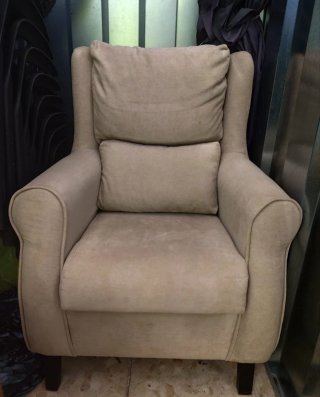 Sillón orejero de color beige con patas de madera