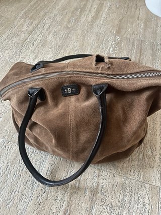 Bolso grande marrón de cuero, con una correa rota.