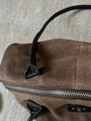 Bolso grande marrón de cuero, con una correa rota.
