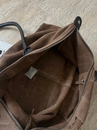 Bolso grande marrón de cuero, con una correa rota.