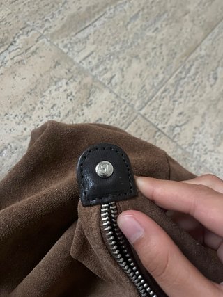 Bolso grande marrón de cuero, con una correa rota.