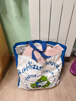 Bolsa grande llena de ropa de mujer variada.