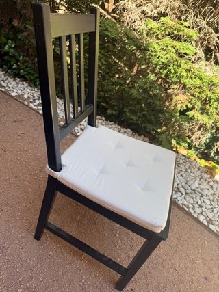 Silla de madera negra con cojín blanco