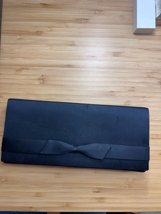 Cartera de mano negra con lazo